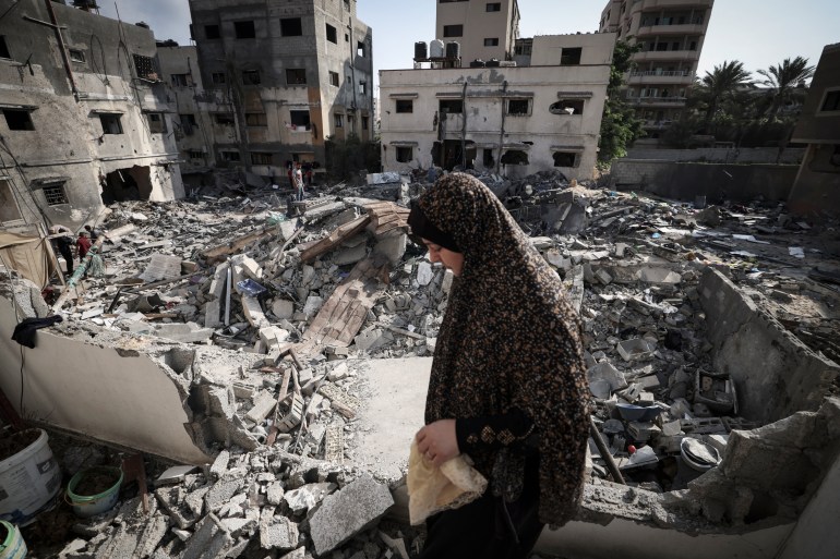 A woman in Gaza walks at the site of a damaged building.