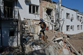 A Ukrainian de-miner climbs debris near the damaged building of a clinical medical laboratory in Kharkiv on August 9 [Sergey Bobok/AFP]