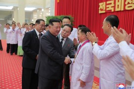 North Korean leader Kim Jong Un greeting with health department officials and scientists in white lab coats at an event in Pyongyang, North Korea.