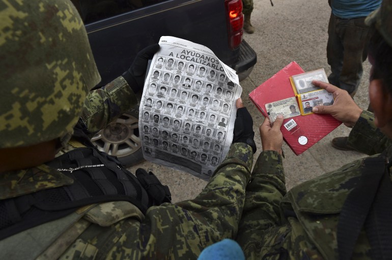 Des soldats mexicains comparant des documents d'identité à une liste d'étudiants disparus en 2014