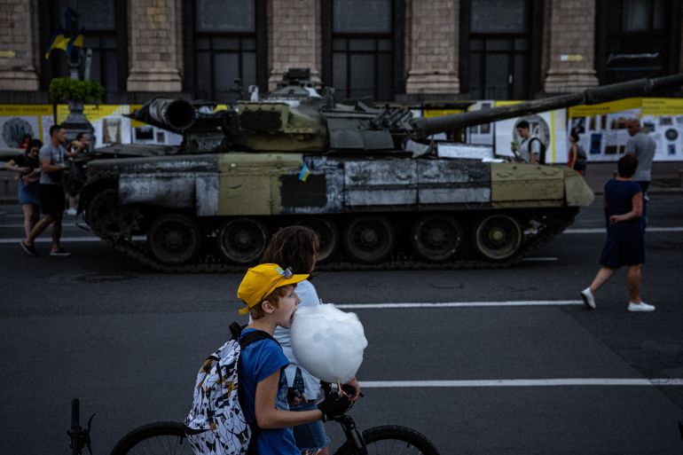 A boy eats candy floss next to a destroyed Russian military equipment at Khreshchatyk street in Kyiv