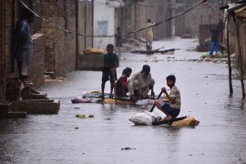 People use makeshift rafts on a waterlogged street in Hyderabad, Pakistan [Akram Shahid/AFP]