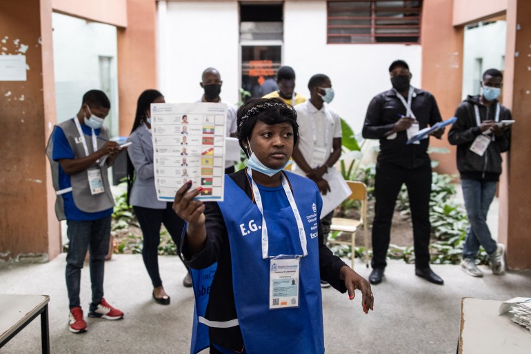 An election official holds up a ballot paper as votes are counted at a polling station in Luanda, Angola.