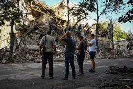 Passers-by stand near a destroyed building following an overnight missile strike in Kharkiv, on August 29, 2022, amid Russia's military invasion launched on Ukraine. (Photo by SERGEY BOBOK / AFP)