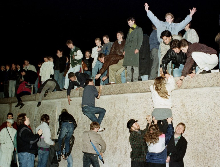 East Germans scramble over the Berlin Wall, the symbol of the divided continent for some 30 years