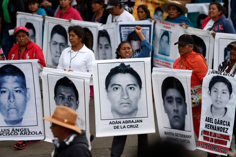 Relatives of the 43 missing students from Ayotzinapa Teacher Training hold portraits of the students during a march