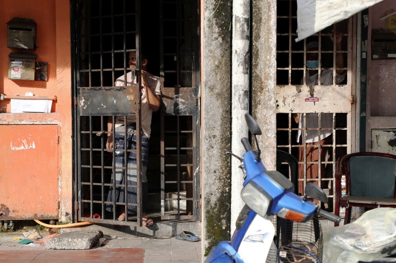 A refugee in Kuala Lumpur watches the street from behind a security gate on his door 