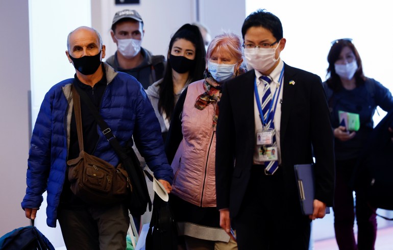 Ukrainians arrive at the airport in Tokyo, Japan, accompanied by a Japanese official