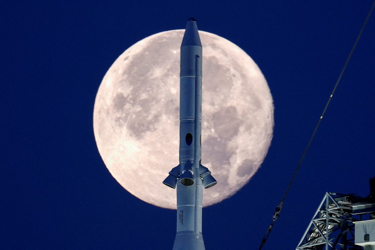 A full moon, known as the "Strawberry Moon", is shown with the top of NASA’s next-generation moon rocket, the Space Launch System (SLS) Artemis 1, at the Kennedy Space Center in Cape Canaveral, Florida.
