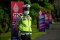 A policeman in a fluorescent jacket and face mask stands guard at a G20 venue in Bali