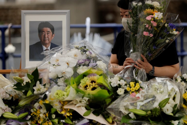 A mourner offers flowers next to a picture of late former Japanese Prime Minister Shinzo Abe