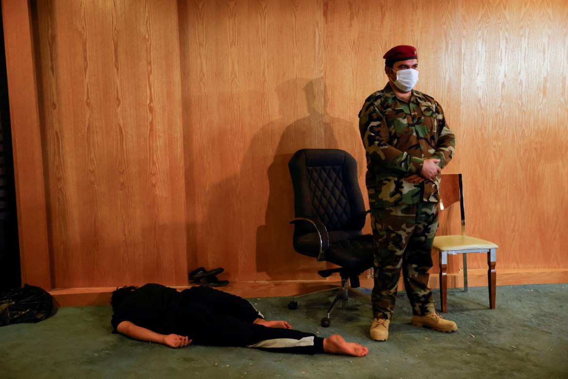 An Iraqi security forces officer stands next to a sleeping supporte