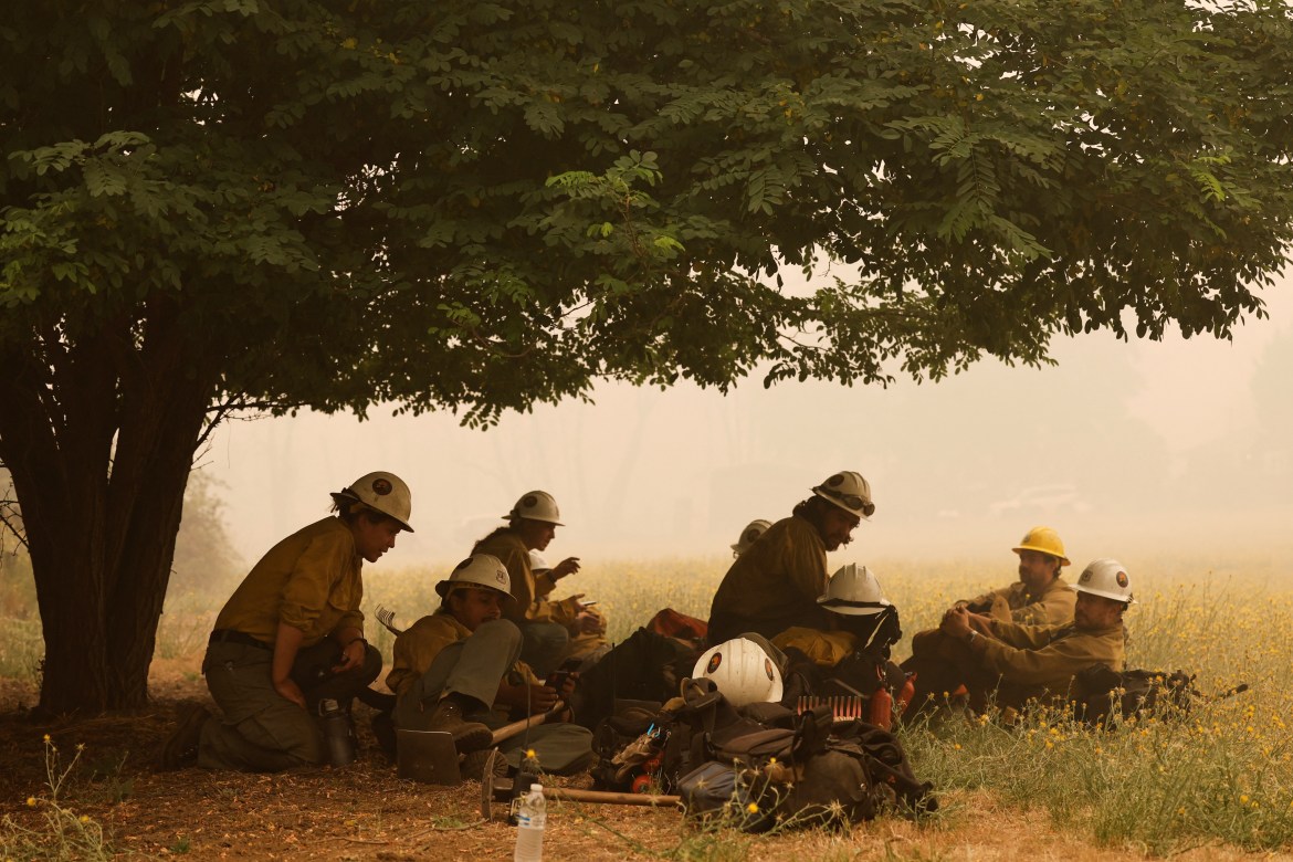 Klamath Interagency Hotshots rest under a tree while waiting for a new assignment as the McKinney Fire burns near Yreka