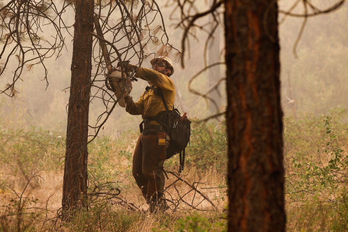 A U.S. Forest Service firefighter clears brush as the McKinney Fire continues burning near Yreka, California