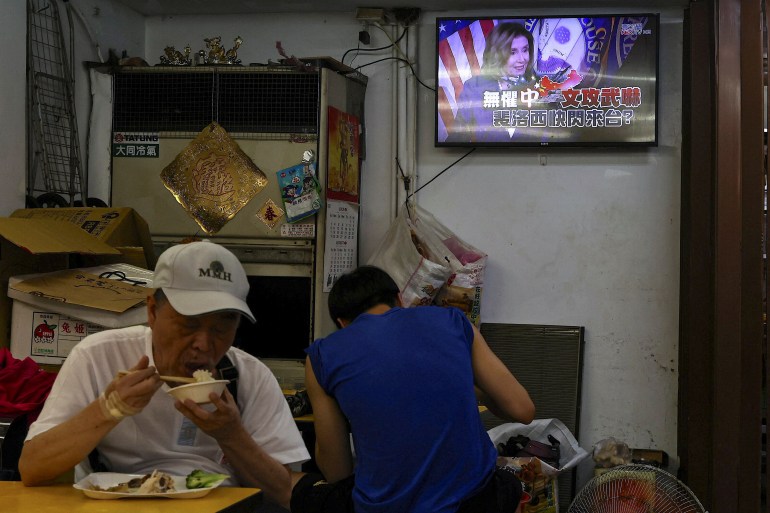 People eat as a television broadcasts news about U.S. House of Representatives Speaker Nancy Pelosi