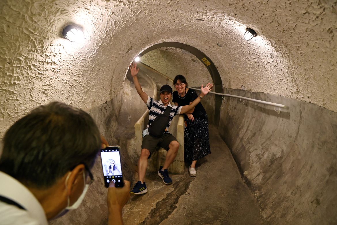 Tourists pose for photos at an underground tunnel that will be used as an air-raid shelter