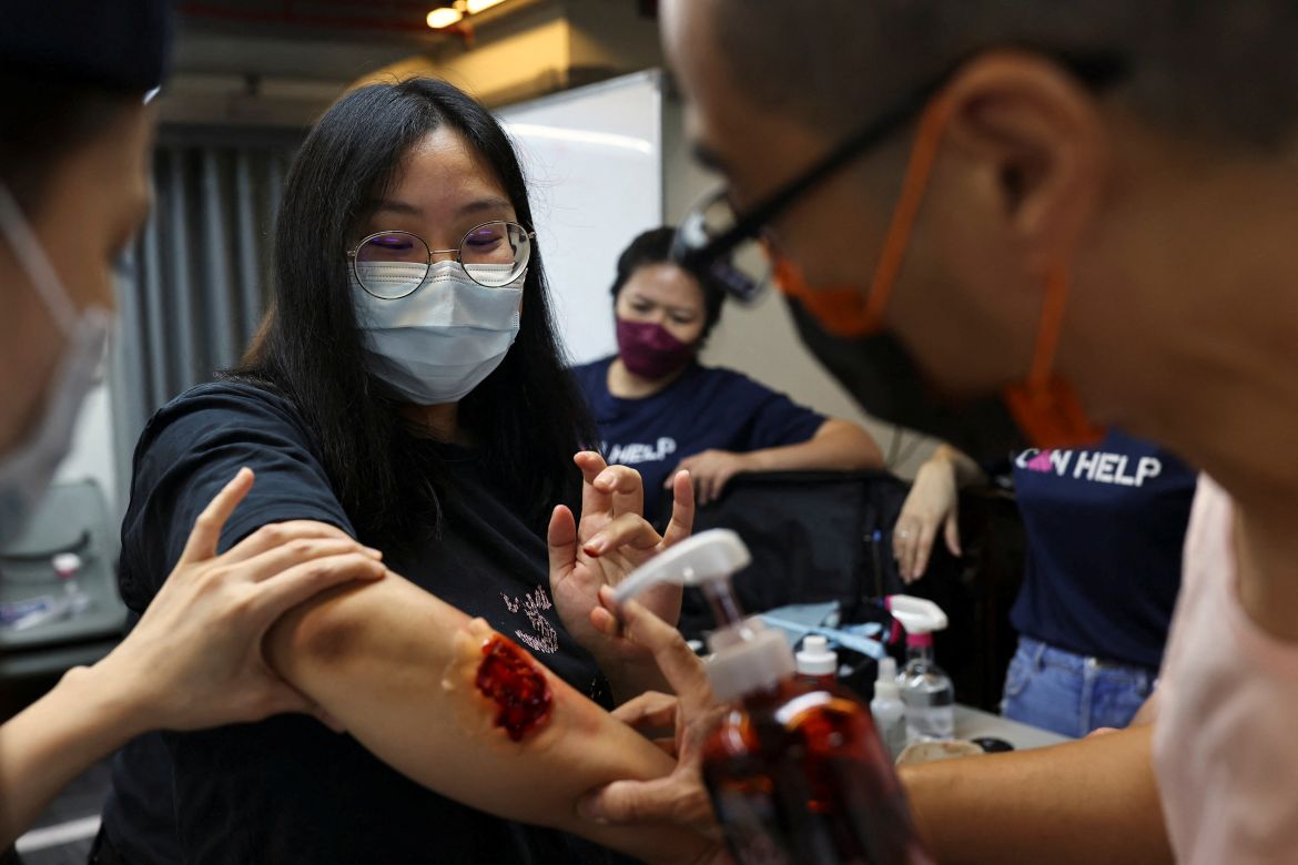 Volunteers place a fake wound on a participant during a first aid training