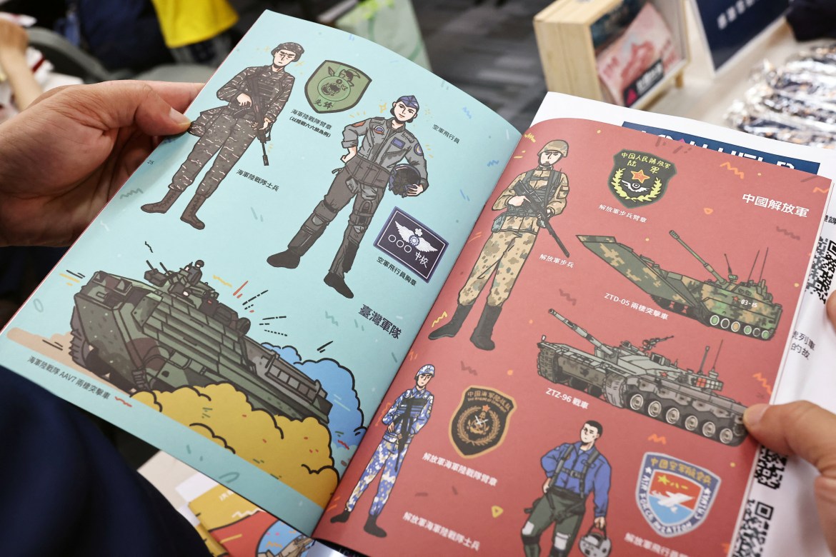 A person holds a booklet with illustrations of Taiwan armed forces and Chinese People's Liberation Army