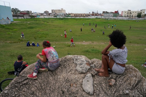 People watch children playing during baseball practice in Havana