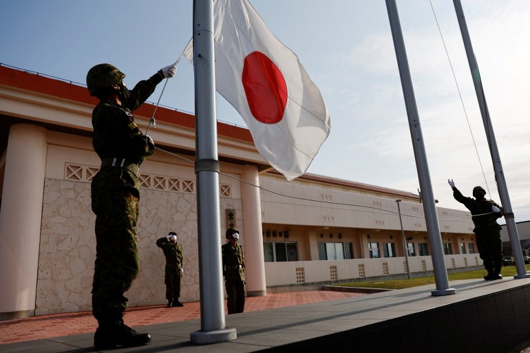 Members of the Japan Ground Self-Defense Force (JGSDF) lower the Japanese national flag in the early evening