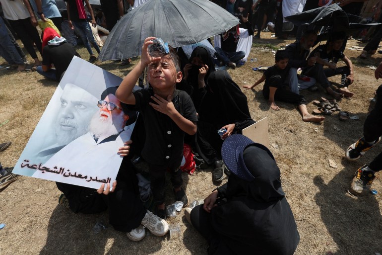 5 Ağustos 2022'de Cuma namazı için toplanan Mukteda es-Sadr'a su döken bir çocuk [Alaa al-Marjani/Reuters]
