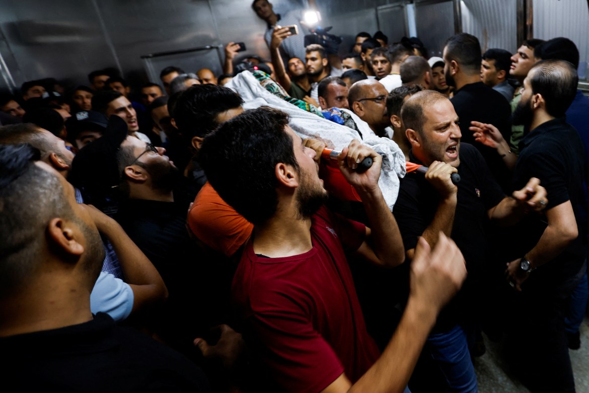 The body of a Palestinian girl is carried by people at a hospital after she was killed during Israeli strikes.