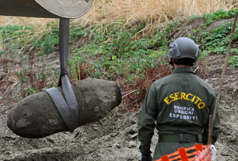 Members of the Italian army remove a World War II bomb that was discovered in the dried-up River Po which has been suffering from the worst drought in 70 years, in Borgo Virgilio, Italy, on August 7, 2022 [Flavio Lo Scalzo/Reuters]