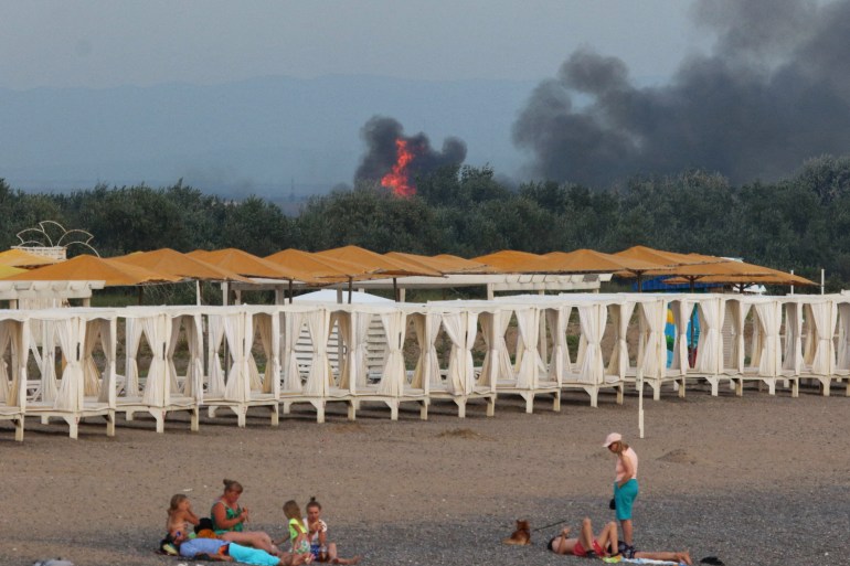 Smoke and flames rise behind beach cabanas after explosions at a Crimea airbase