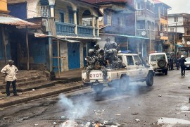 Riot police patrol as they pass smoke rising from a roadblock during anti-government protests in Freetown, Sierra Leone [Umaru Fofana/Reuters]