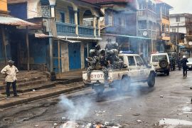 Riot police patrol as they pass smoke rising from a roadblock during anti-government protests in Freetown, Sierra Leone
