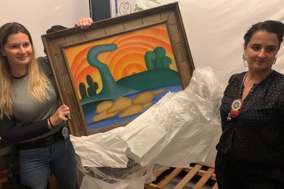 Policia Civil investigator and a delegate hold artist Tarsila do Amaral's painting titled 'Sol Poente' after it was seized during a police operation in Rio de Janeiro, Brazil