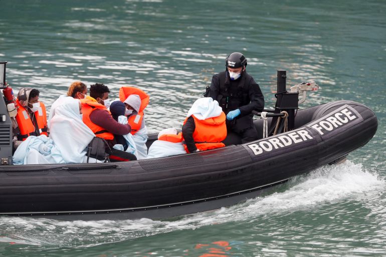Border Patrol agents bring migrants into Dover harbour on a boat