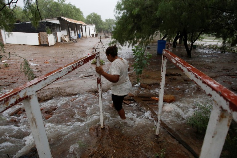 A woman stands near flooding in Mexico