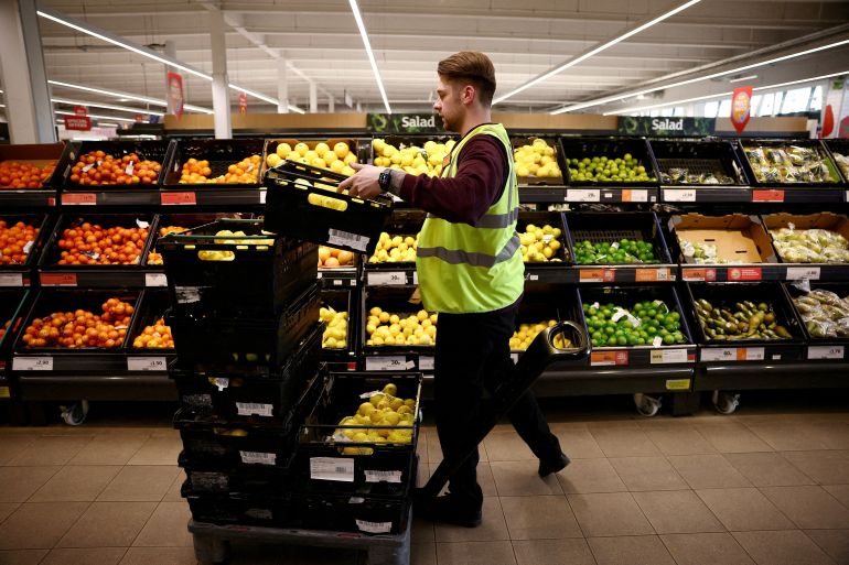 An employee arranges produce at a supermarket in Richmond, London