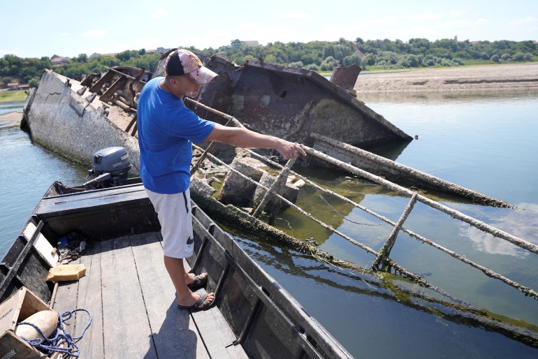 Ivica Skodric, un vieux pêcheur local, inspecte l'épave d'un navire de guerre allemand sur le Danube à Prahovo, en Serbie, le 18 août 2022. [Fedja Grulovic/Reuters]