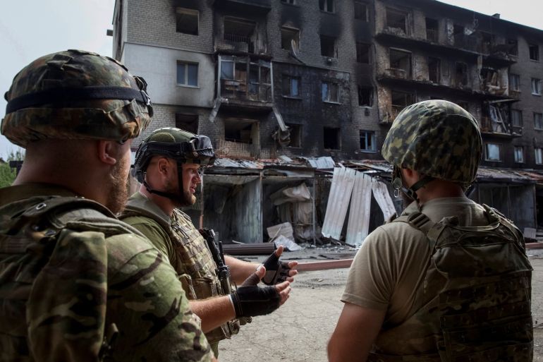 Ukrainian service members speak to each other in front of a residential building damaged by a Russian military raid in the town of Siversk, Ukraine.