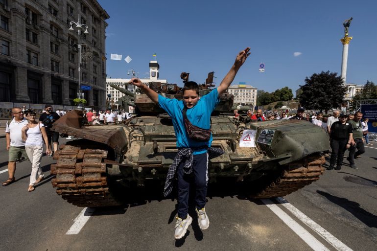 A boy jumps from a tank at an exhibition of destroyed Russian military vehicles and weapons in the centre of Kyiv, Ukraine.