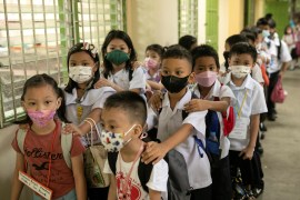 Students wearing masks for protection against the coronavirus disease (COVID-19) prepare to enter their classrooms on the first day of in-person classes at a public school in San Juan City, Philippines