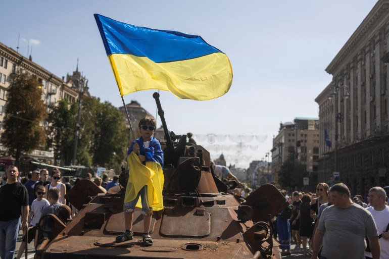A boy is seen waving a Ukrainian flag at an exhibition of destroyed Russian military vehicles in Kyiv
