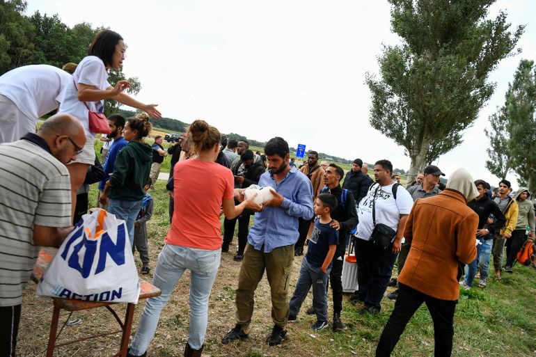 Volunteers hand out hygiene packages to refugees waiting outside the main reception centre for asylum seekers, in Ter Apel, Netherlands on August 26, 2022 [Piroschka van de Wouw/Reuters]