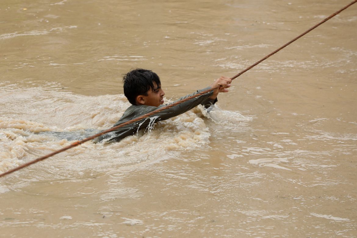 A boy crosses a flooded street