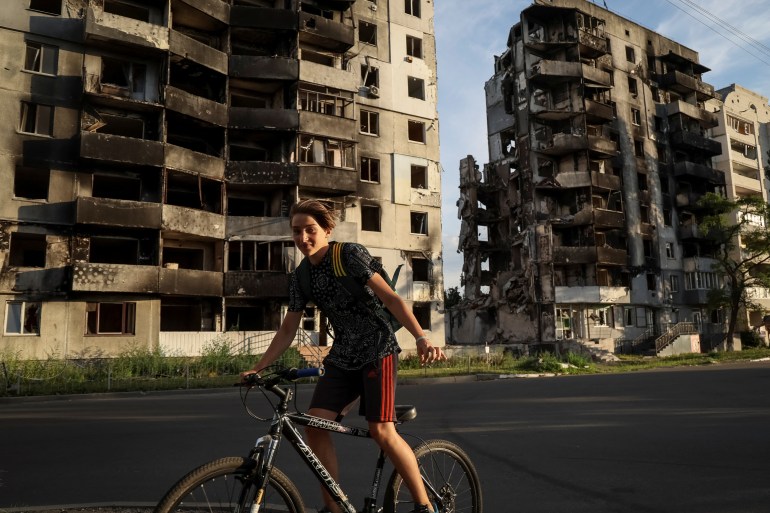 A boy rides a bike in front of destroyed buildings amid Russia's invasion of Ukraine, in the town of Borodianka, in Kyiv region, Ukraine August 26, 2022. REUTERS/Gleb Garanich
