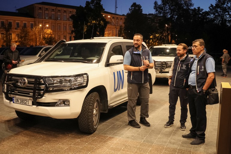Members of International Atomic Energy Agency (IAEA) mission stand by UN vehicles at hotel in Kyiv.