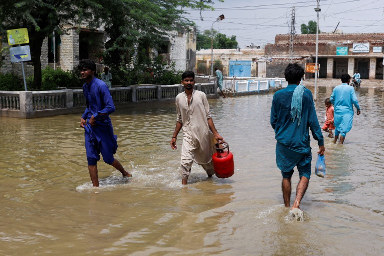 Des hommes traversent une rue inondée à Jacobabad, au Pakistan. 