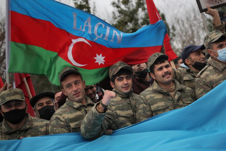 Azerbaijani soldiers with a national flag with the words "Lachin" celebrate the transfer of the Lachin region to Azerbaijan's control,