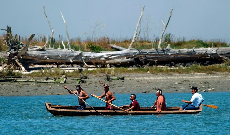 A photo of members of the Wiyot Tribe paddling in a dugout redwood canoe.