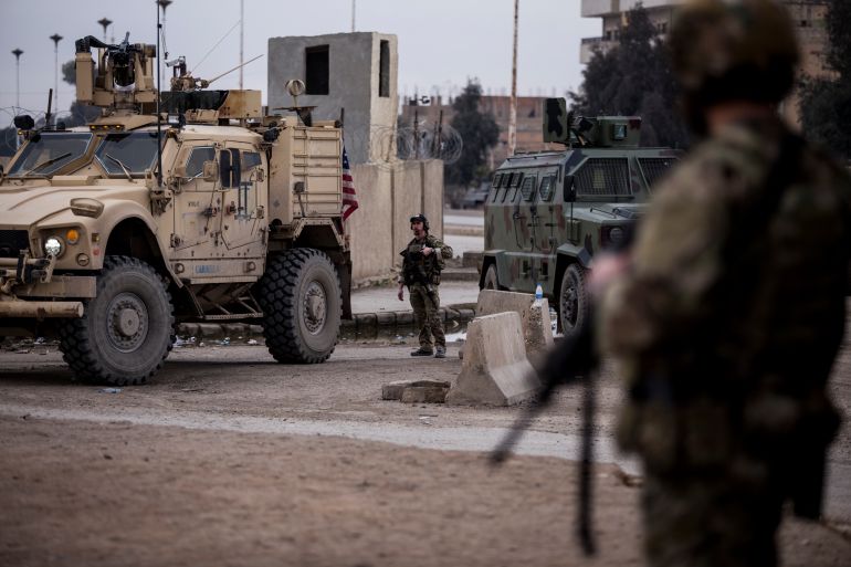 US soldiers in Syria in front of an armoured vehicle