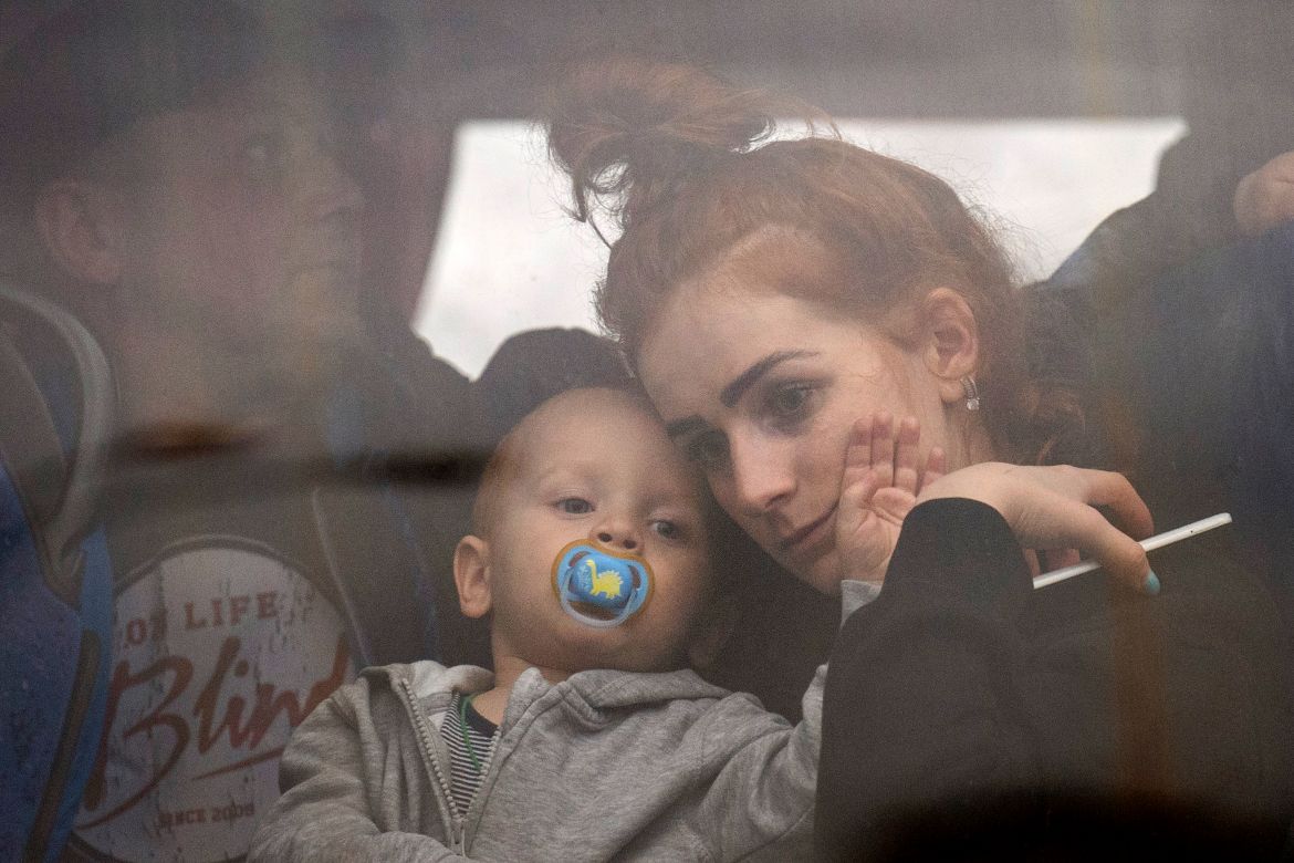 A woman holds her baby inside a bus as they leave Kyiv, Ukraine,
