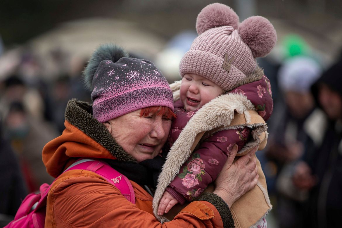A woman holding a child cries after fleeing from the Ukraine and arriving at the border crossing in Medyka, Poland