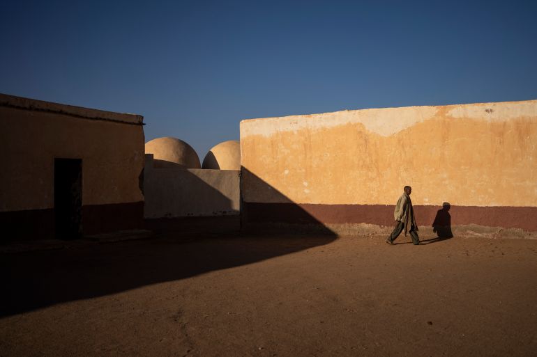 a man walks in front of a sand-coloured wall at a school in Western Sahara